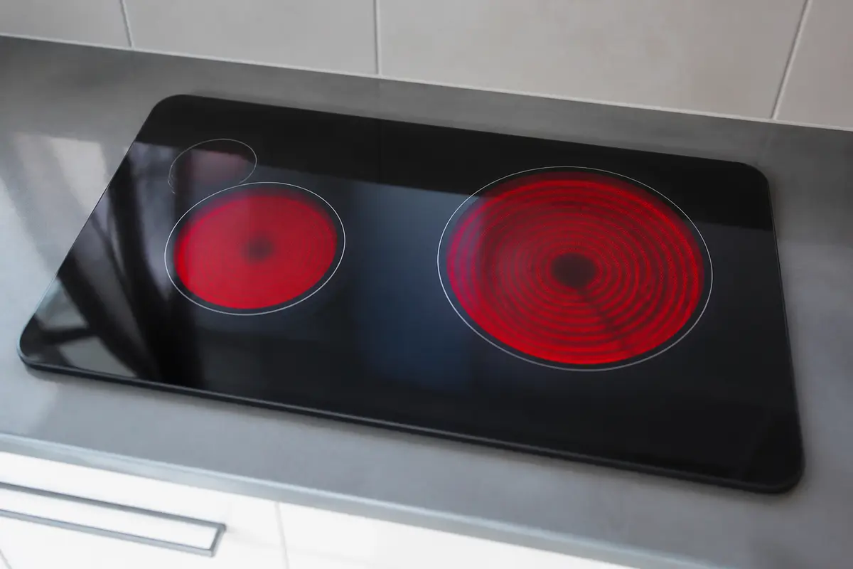 Plaque chauffante active avec domino vitrocéramique rouge sur plan de travail.