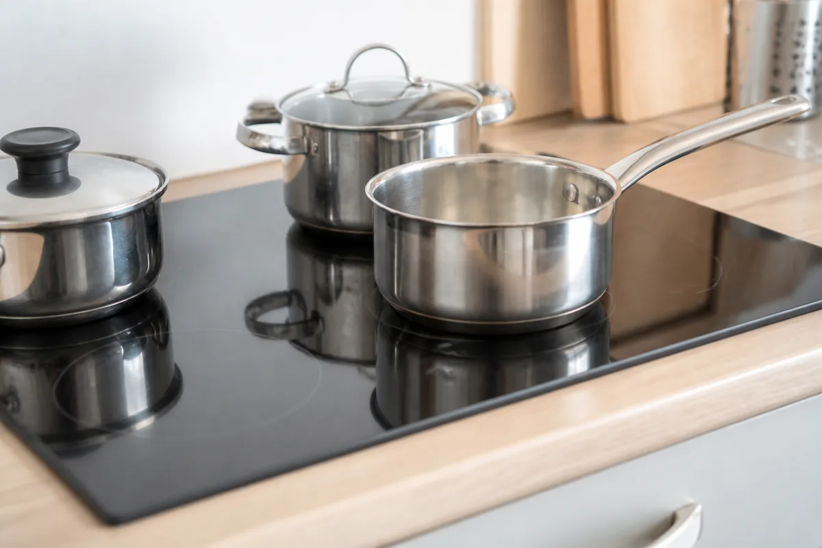 Plaque de cuisson vitrocéramique 4 feux intégrée dans une cuisine moderne avec casseroles