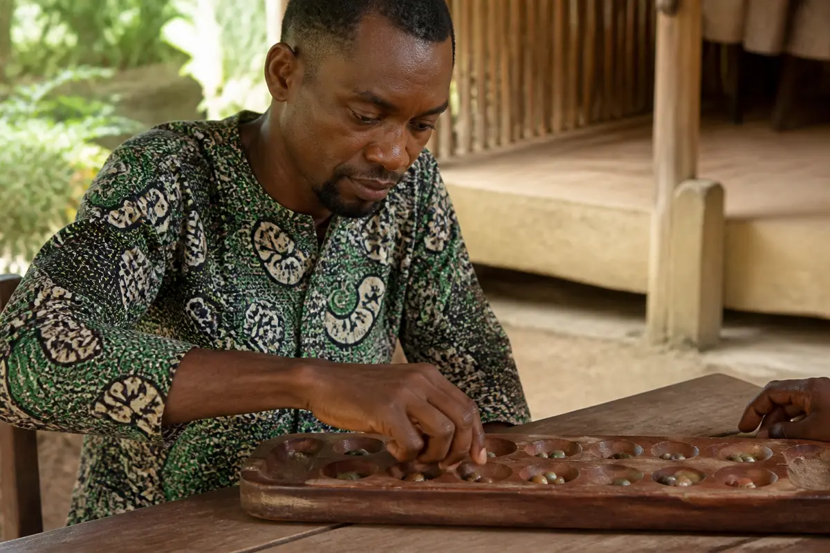 Homme jouant au jeu traditionnel africain Congkak avec une planche en bois et des graines